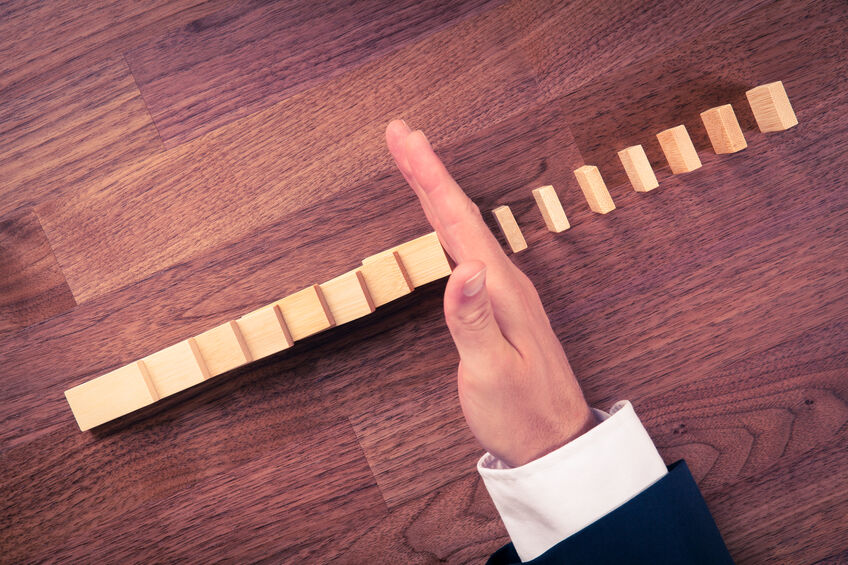 hand stopping dominoes from falling