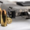 .45 or 11 mm. ammunitions and automatic hand gun on white background